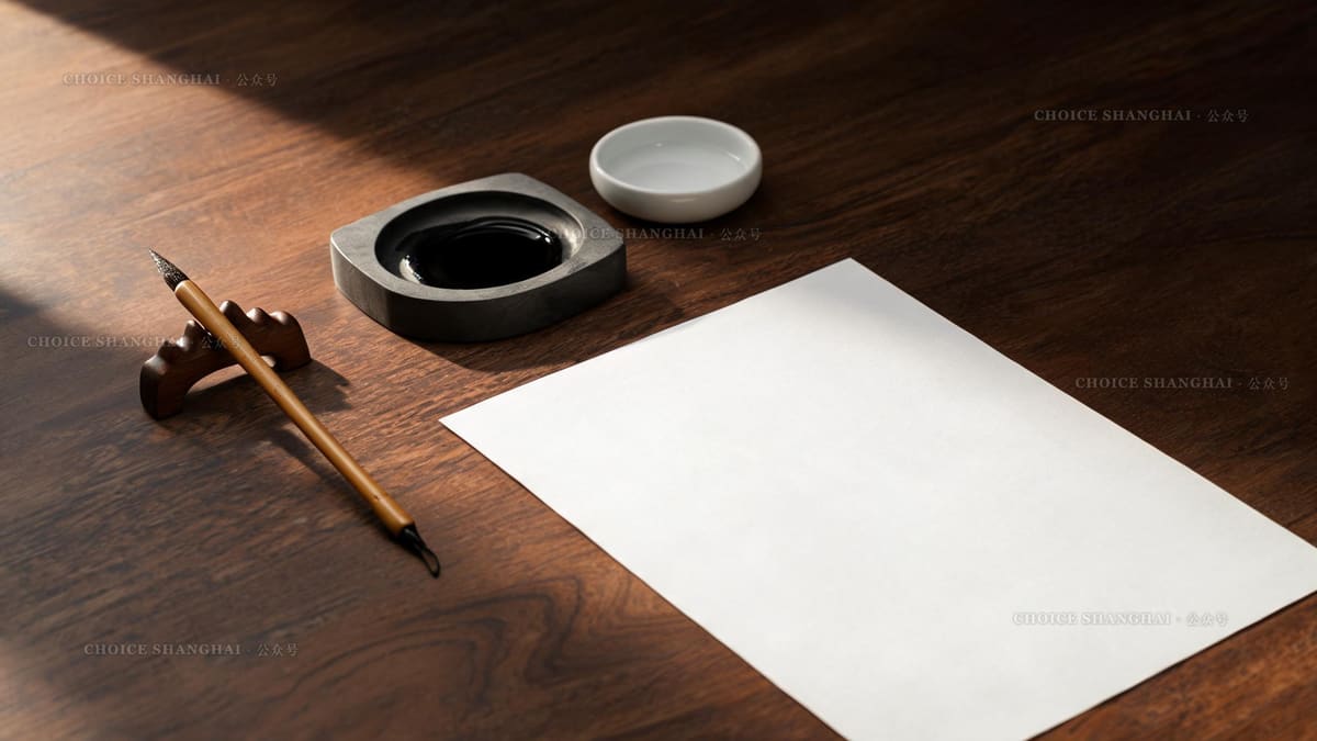 A Chinese calligraphy still life with a bamboo brush, ink stone and blank paper on a dark wooden desk