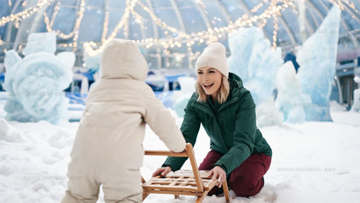 Mother in a forest green shell laughing as her child pushes a wooden sled through powder snow under a dome strung with warm lights
