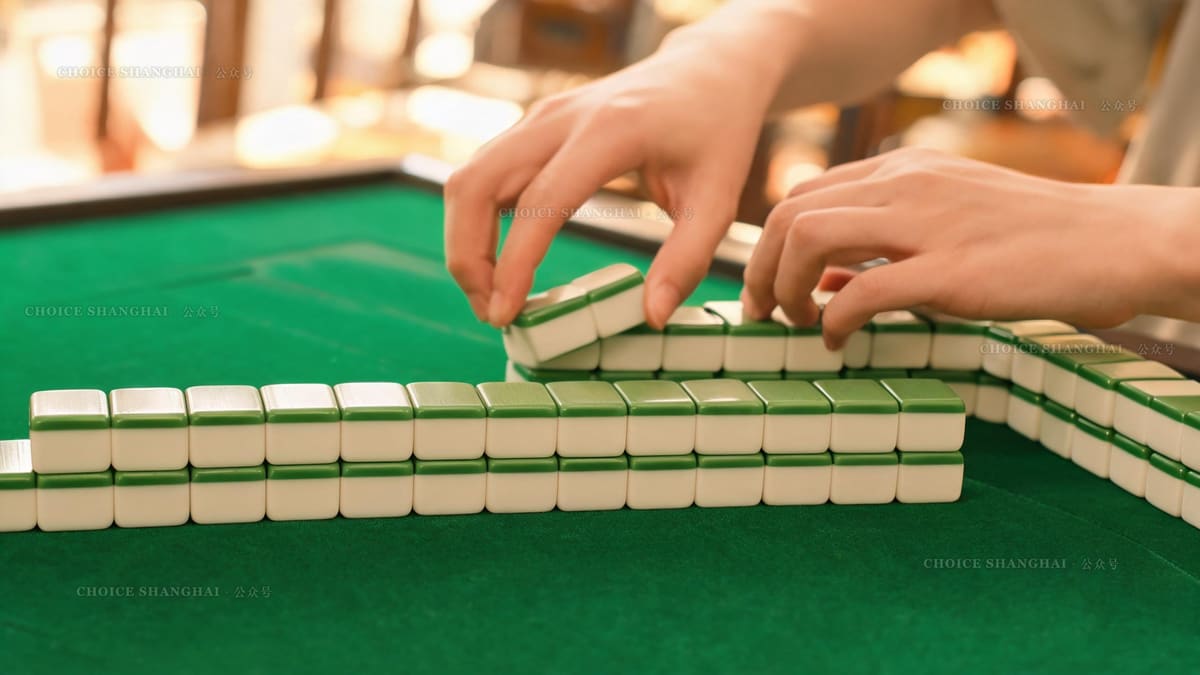 A close-up of ivory and green mahjong tiles stacked into a wall on a green felt table in a Shanghai teahouse