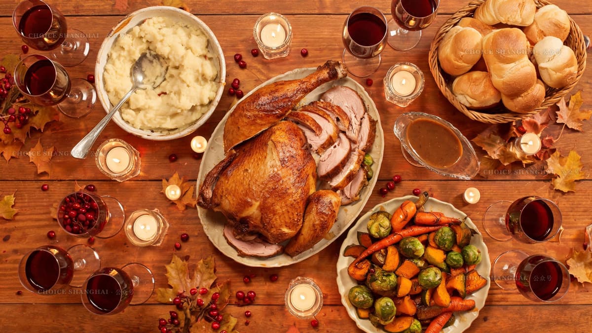 A Thanksgiving dinner spread on a restaurant table with carved turkey, sides, gravy and red wine in candlelight