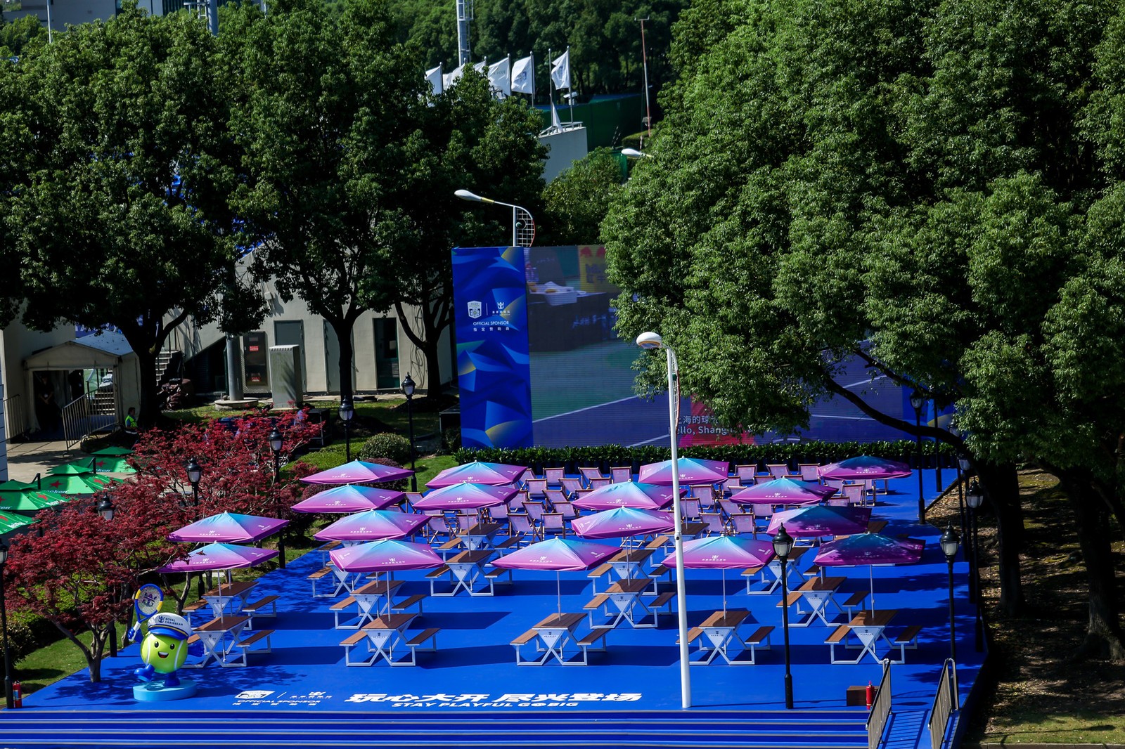 The outdoor food village at the Shanghai Masters with shaded picnic tables under umbrellas