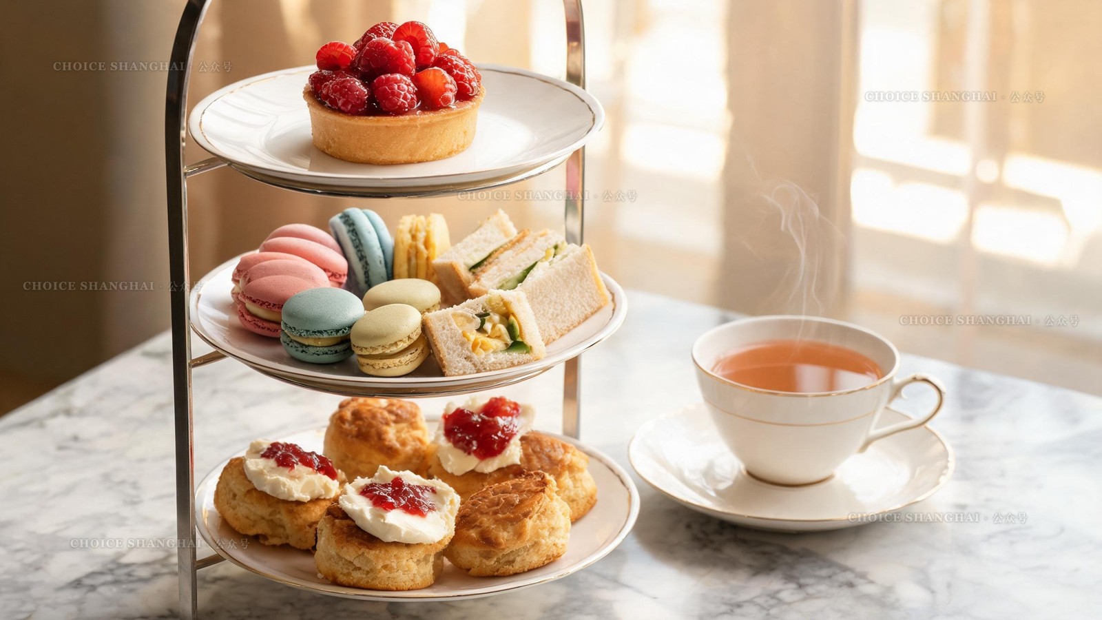 Three-tier afternoon tea stand with clotted-cream scones, macarons, finger sandwiches and a fruit tart beside a steaming cup of tea