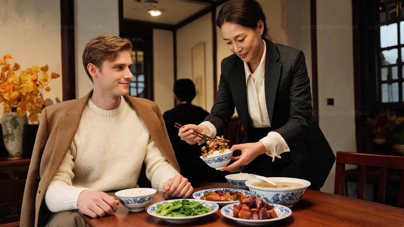 An older woman warmly placing food into a European man's bowl with chopsticks at a Chinese family dinner in Shanghai