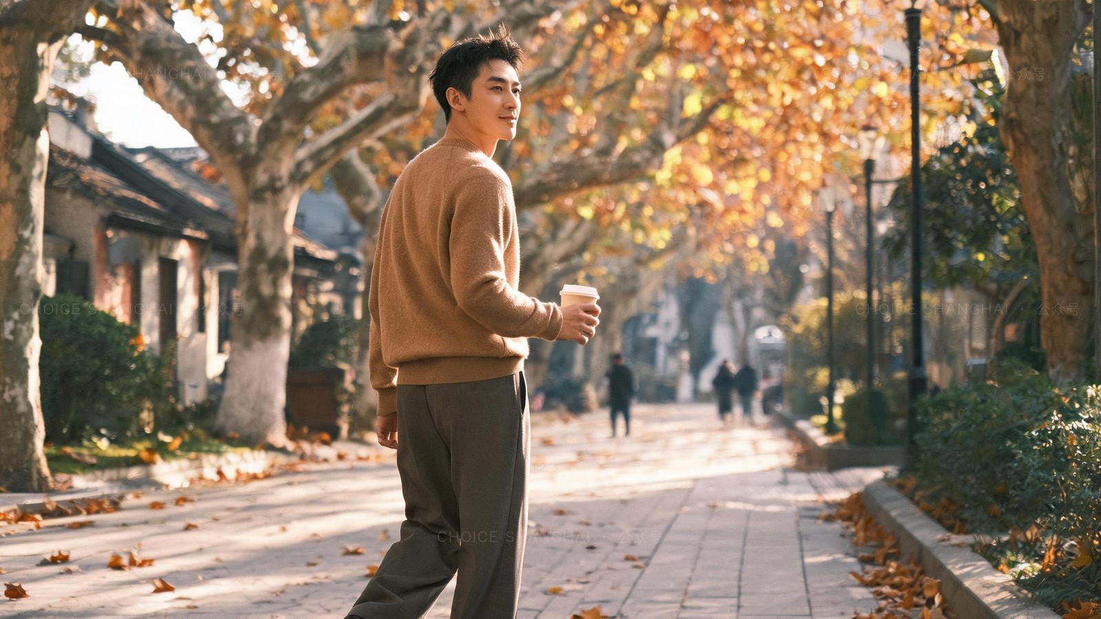 A person taking a slow morning walk through a quiet tree-lined Shanghai park with a cup of coffee, autumn light, a small restorative moment away from work
