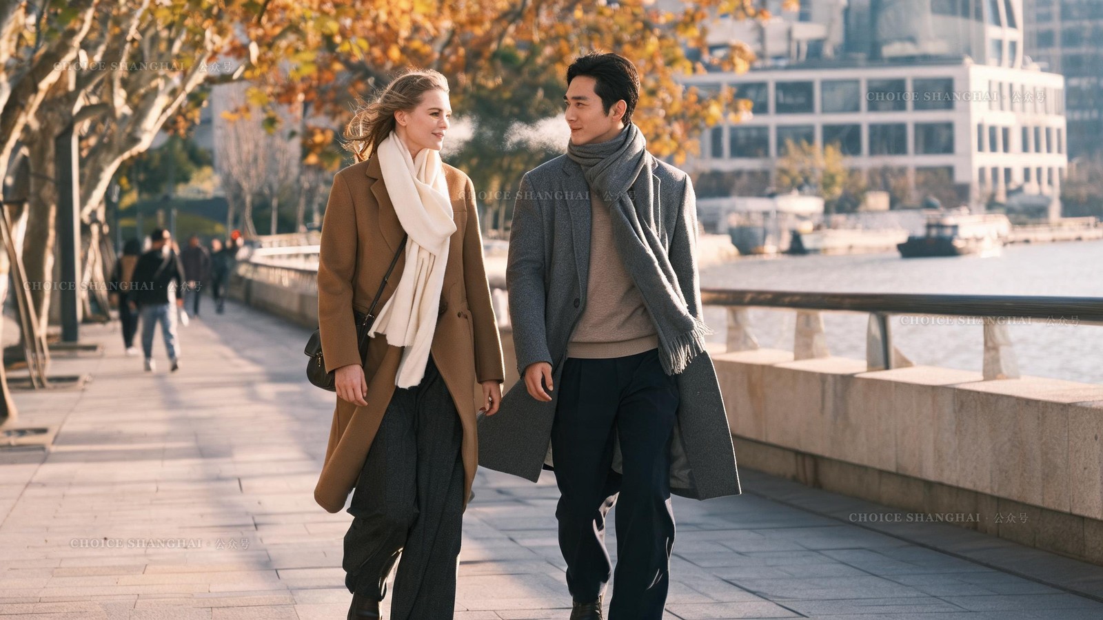Two friends in wool coats and scarves walking a sunlit Shanghai riverside on a crisp clear winter day, breath visible, smiling