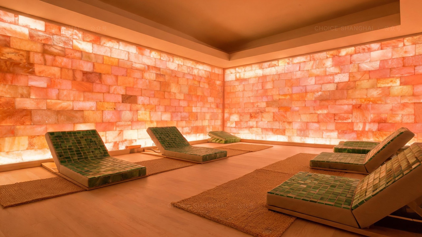 A Korean-style salt sauna room in a Shanghai bathhouse with glowing Himalayan salt-brick walls and green jade-tile recliners on woven mats