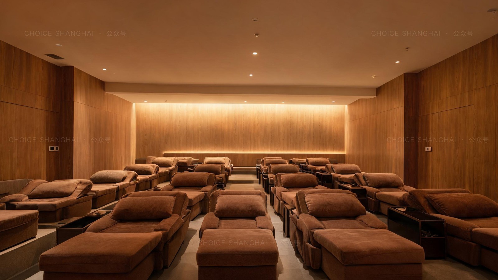 A warm communal rest lounge in a Chinese bathhouse with rows of plush reclining chairs under soft dim lighting