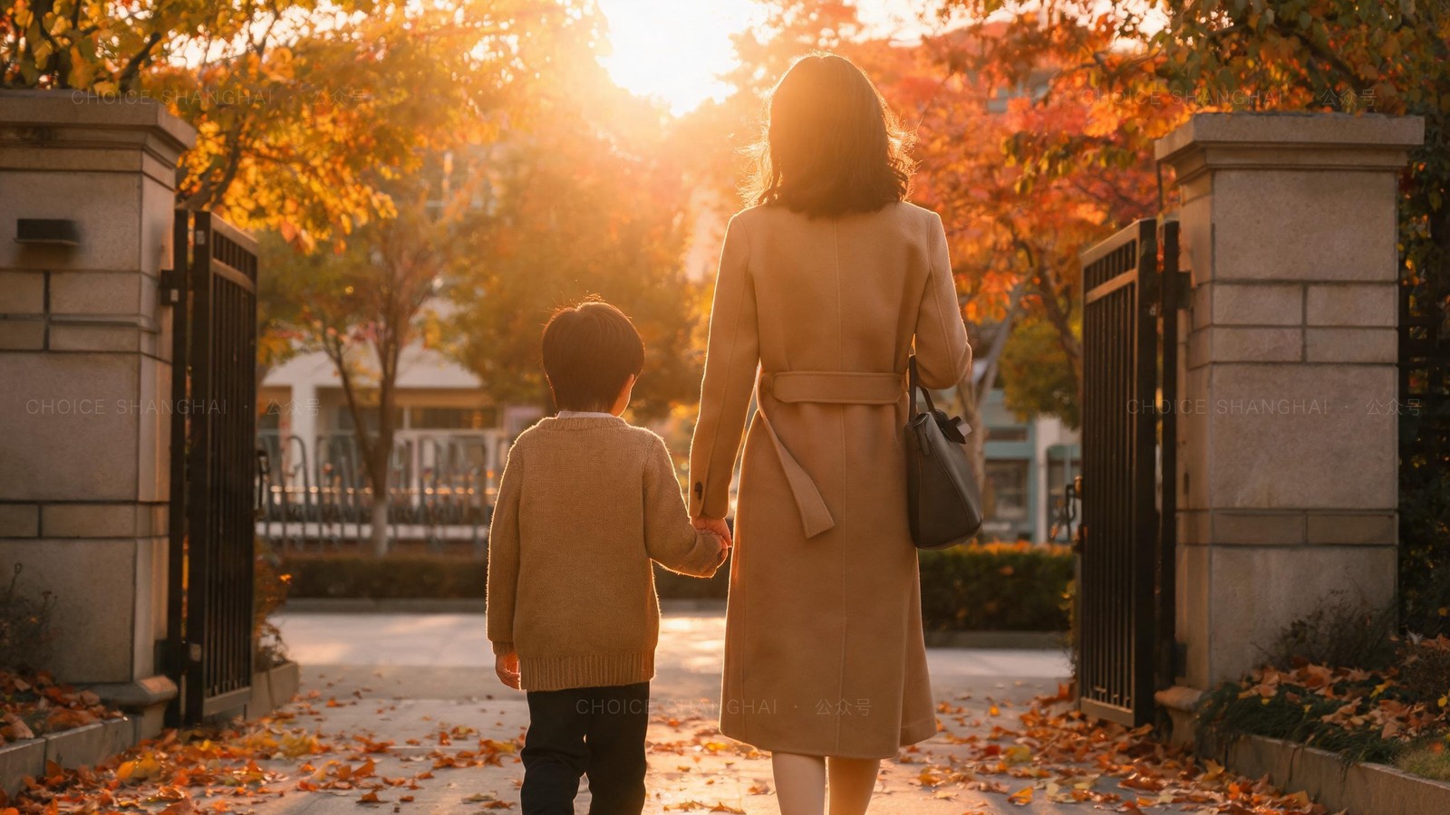 A mother and child walking hand in hand through a school gate at golden hour among autumn leaves