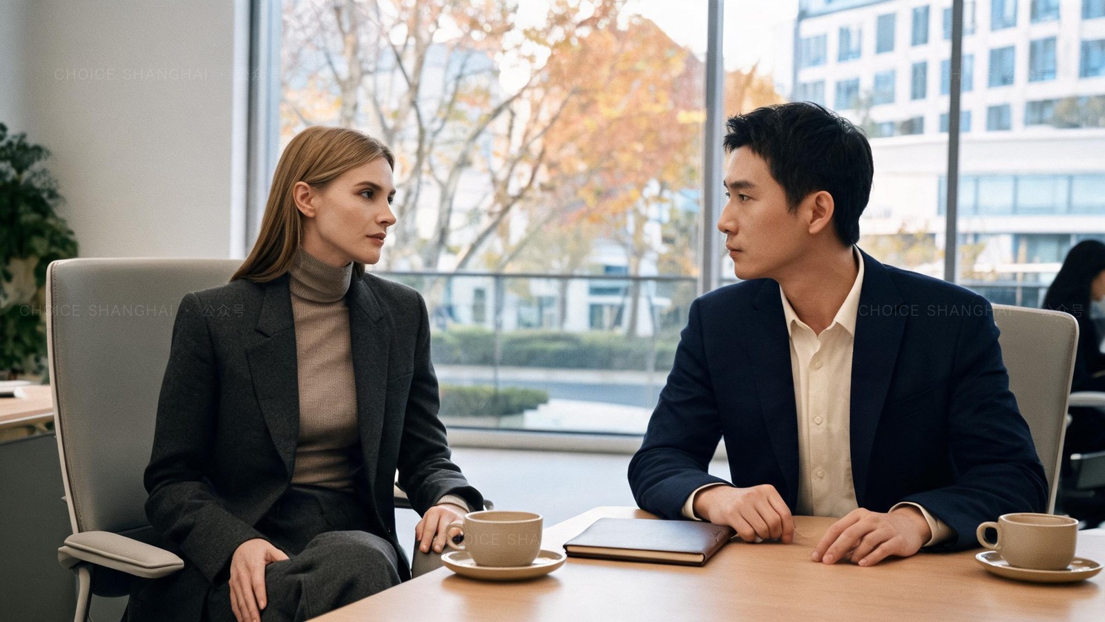 A woman in a charcoal blazer in a calm, confident salary conversation with a manager across an office table in Shanghai