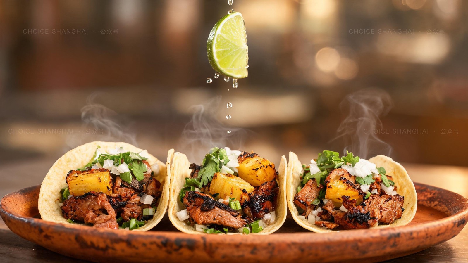 Three tacos al pastor with charred pork, grilled pineapple, cilantro and onion on a terracotta plate, lime squeezed over the top