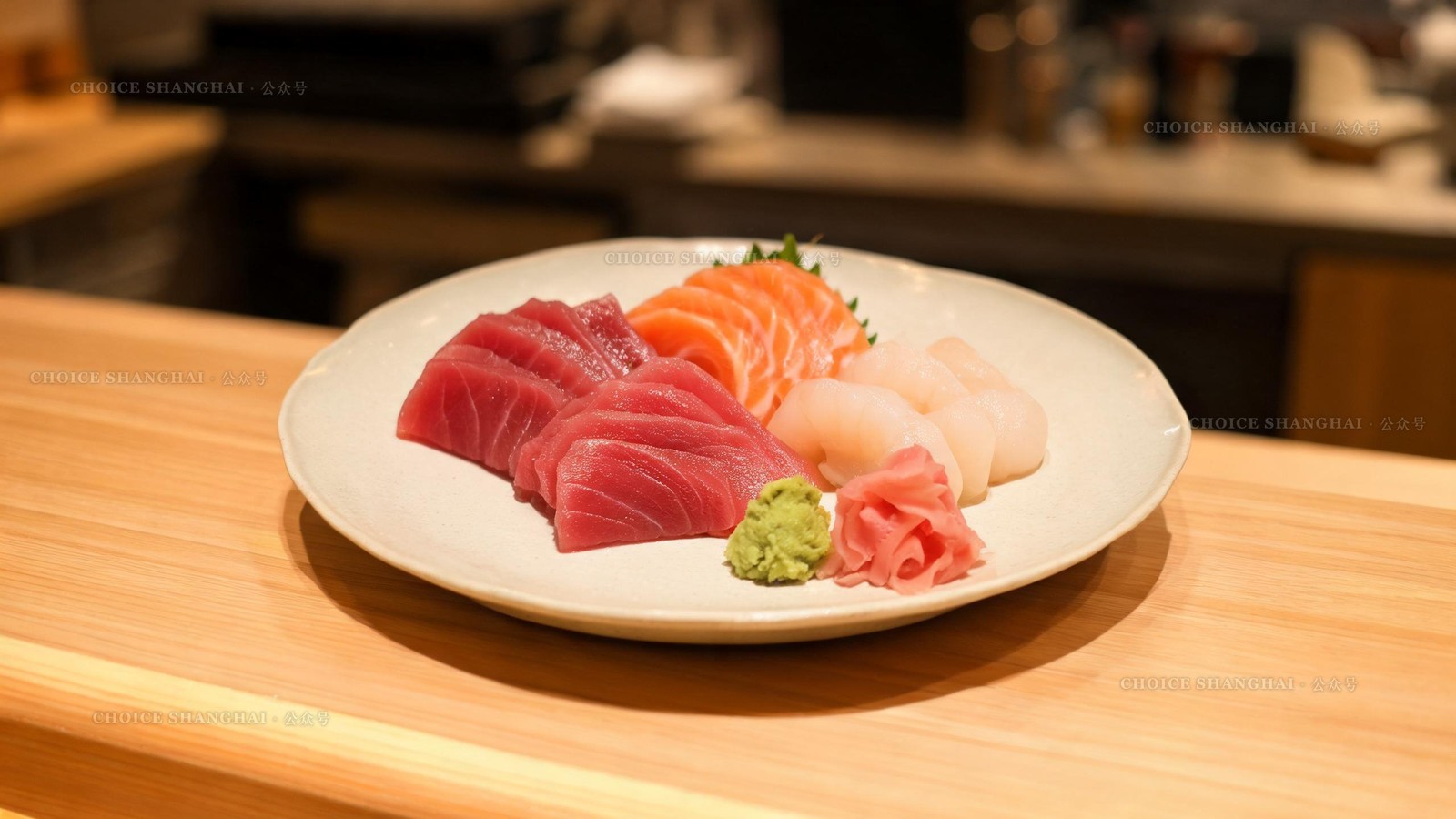Platter of fresh tuna, salmon and scallop sashimi on a pale ceramic plate at a Shanghai sushi counter