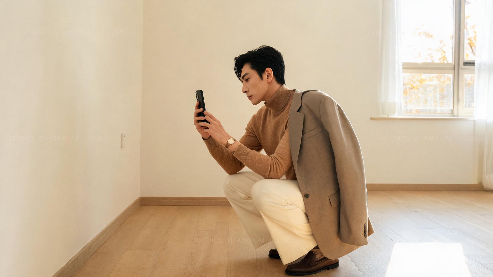 A man in a camel knit photographing the clean wall and floor of an empty Shanghai apartment on move-out day to document its condition