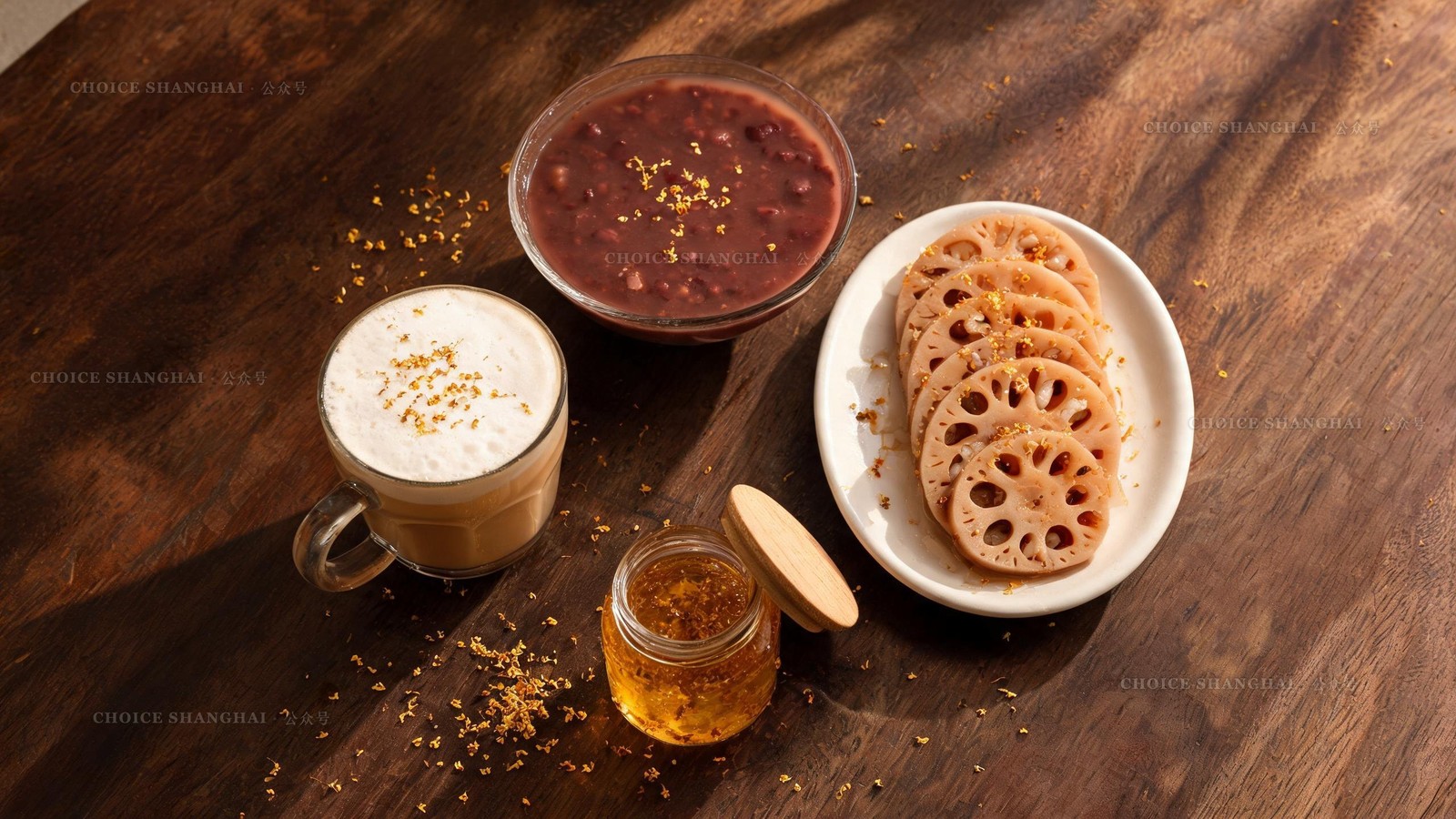 Osmanthus autumn sweets on a dark wood table: candied-osmanthus lotus root, osmanthus red-bean soup, a jar of golden syrup and an osmanthus latte sprinkled with flowers