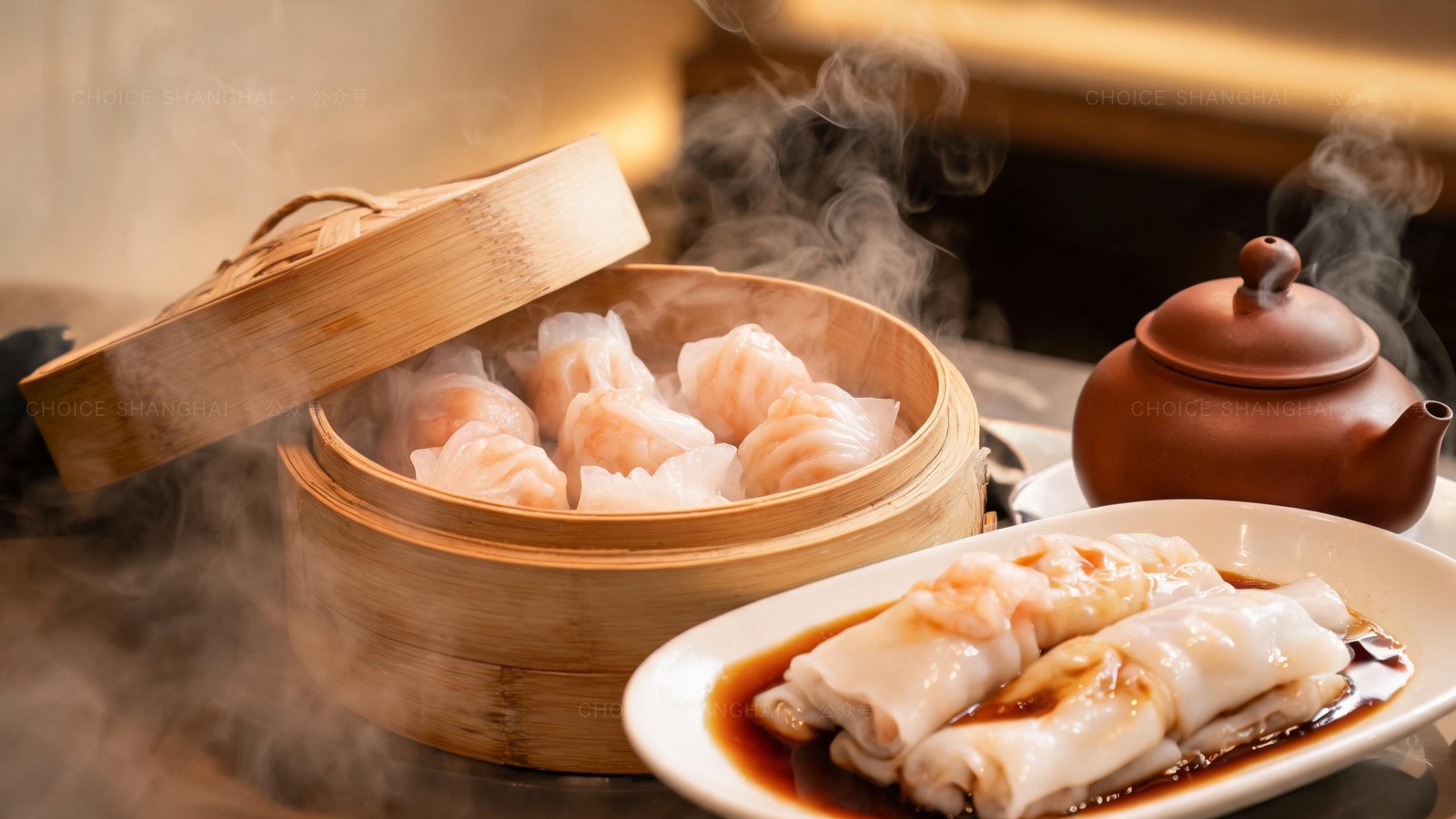 Close-up of a bamboo steamer of translucent har gow shrimp dumplings and a plate of glossy cheung fun rice noodle rolls with soy sauce, a pot of oolong tea beside them