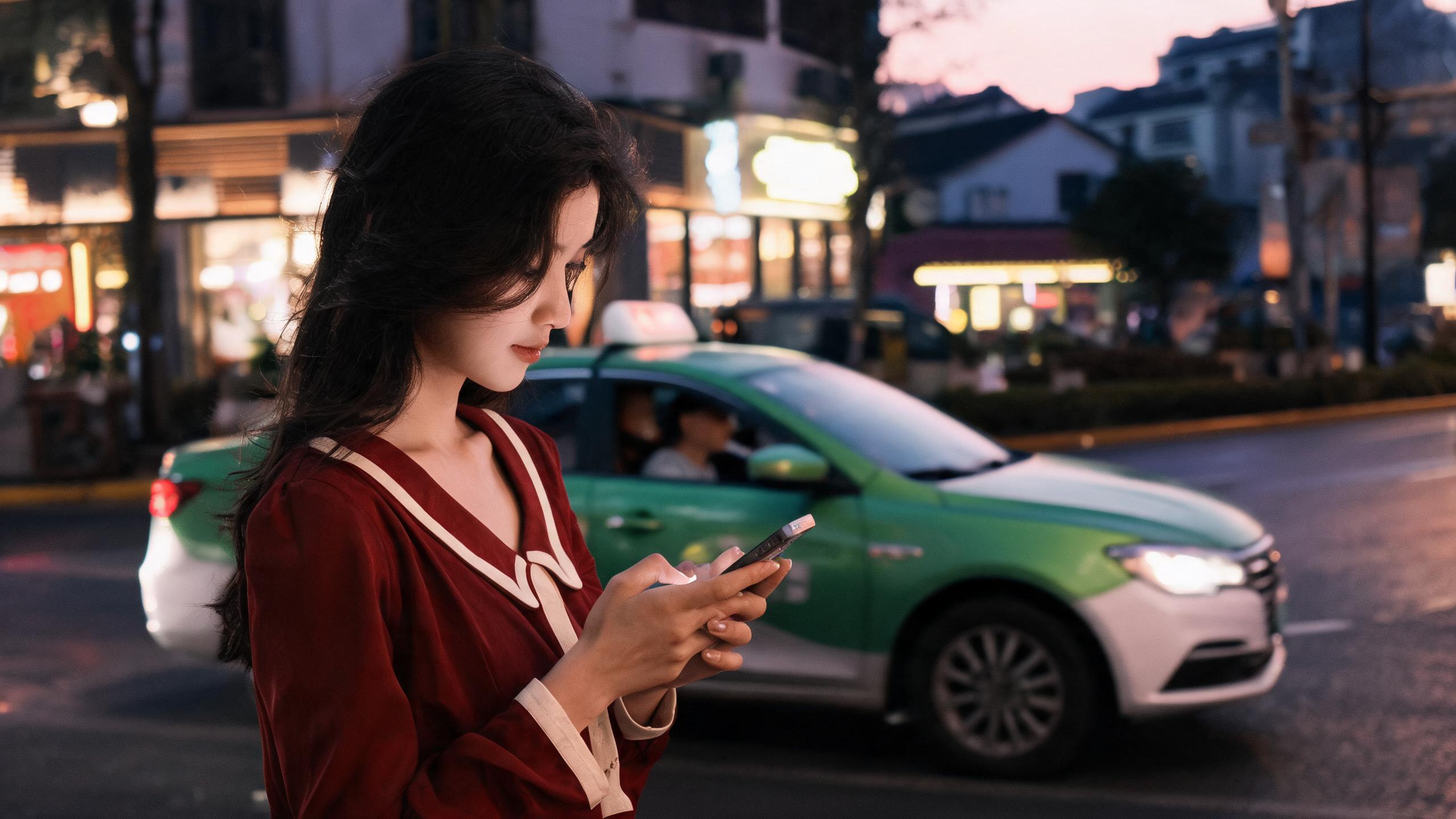 Woman on a Shanghai street corner checking her phone as a taxi waits