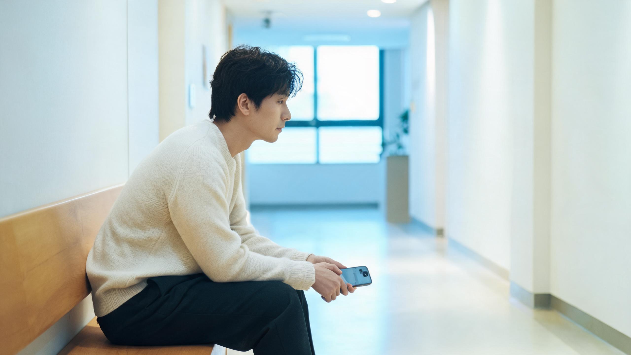 A man waiting on a bench in a calm clinic corridor in Shanghai